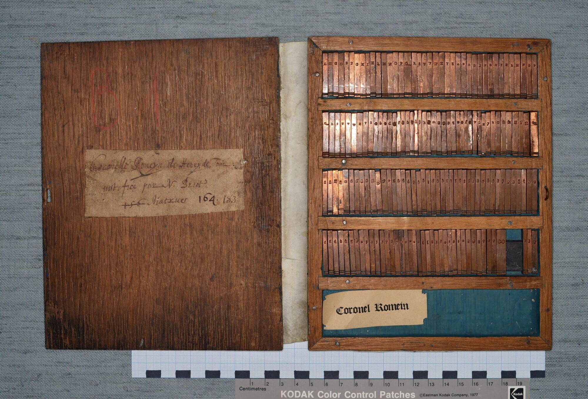 These are matrices---the pieces of copper that are the molds used to produce pieces of type---used for the typeface Coronelle Romaine. If you zoom in, you can see the nicks at the bottom of the matrices used to orient them in the mold and the individual letter forms, as well as ligatures (joined letters), numbers, and assorted other characters. Stamps made to illustrate this typeface can be seen here.